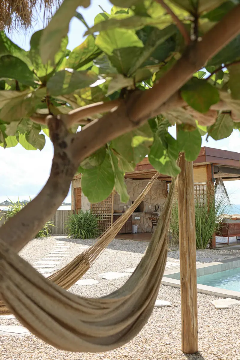 Rede armada sob uma figueira, com a piscina e o gazebo ao fundo