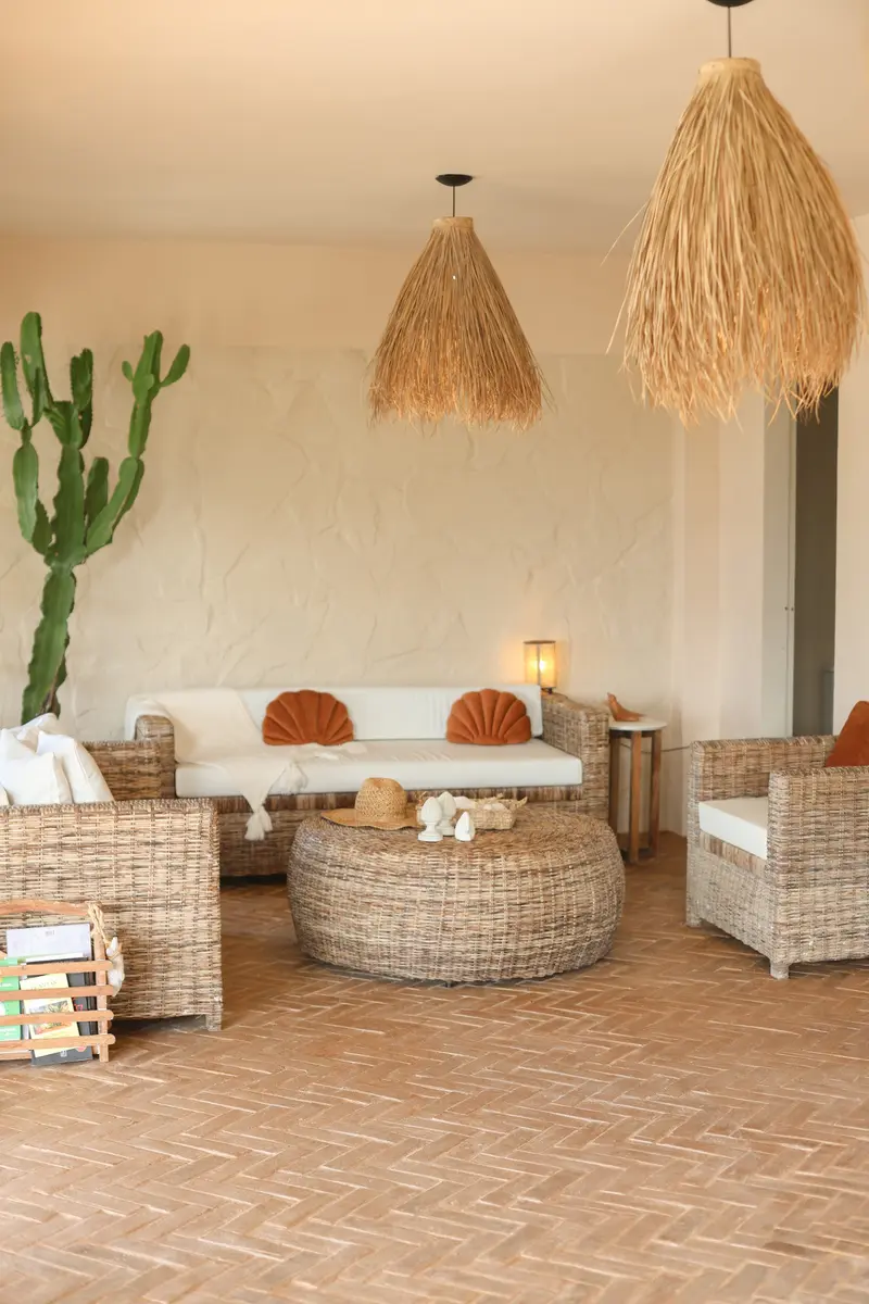 Sala com sofás de palhinha, cacto e pendentes de palha