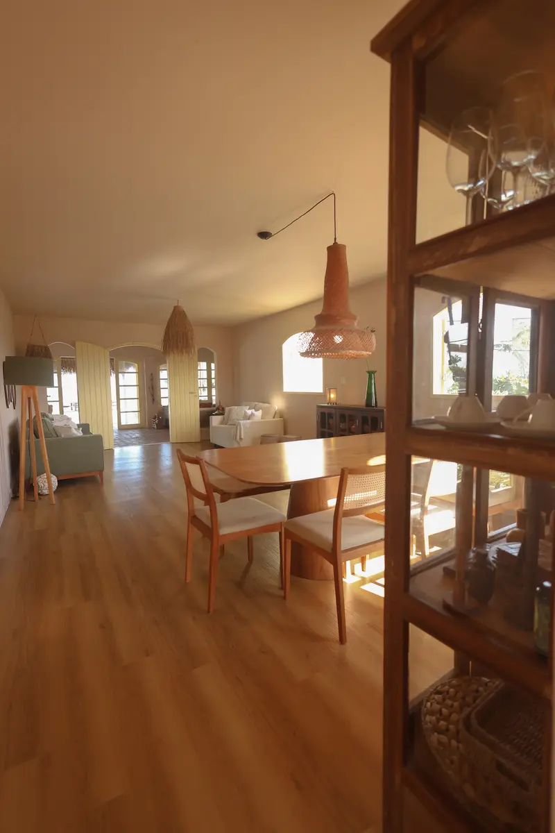 Sala de jantar com cristaleira de madeira e a sala de estar ao fundo