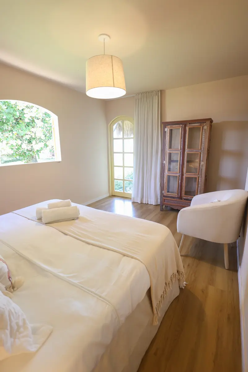 Quarto com cama queen e poltrona branca