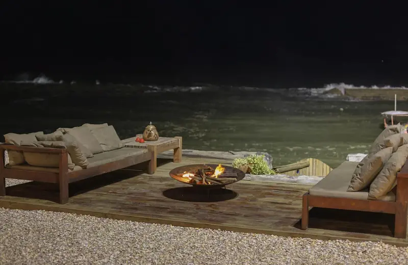 Deck à noite com o fogo aceso e o mar escuro ao fundo